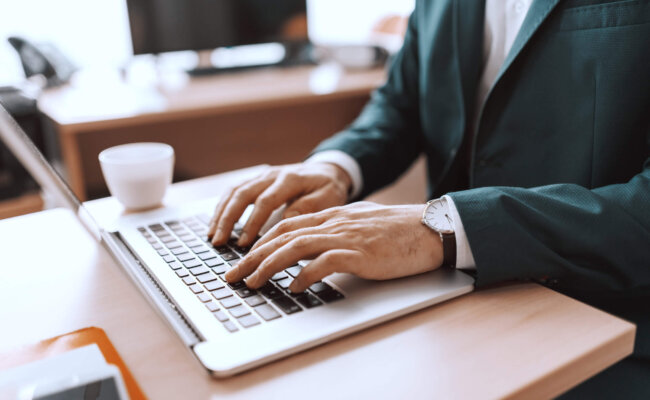 Close up of Caucasian businessman typing on keyboard. Office interior.